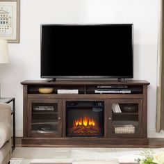 a flat screen tv sitting on top of a wooden entertainment center next to a fire place