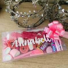 a pink box filled with candy and candies on top of a wooden table next to some branches