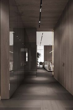 an empty hallway with glass partitions and wooden walls on both sides is lit by recessed lighting