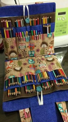 a case filled with lots of colorful pencils on top of a table next to a pile of books