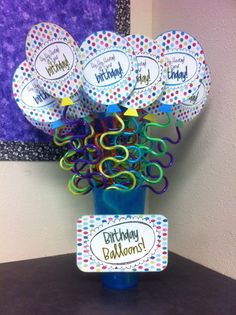 a blue vase filled with lots of balloons and confetti on top of a table