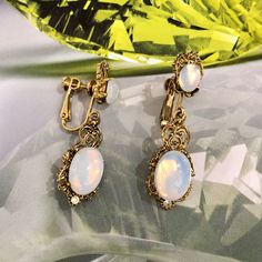 Clip-on earrings Material: gold metal Cabochon: milky white or brown Crystal: white Width: 1.30 cm (0.51") Height: 4.60 cm (1.18") Engraved on the back of the earrings its serial number, "E422". All our items are vintage and are made by Sphinx, a renowned English company that closed its doors in the early 2000s and if they seem new to you it is because they come from an unsold stock so never worn but nevertheless vintage. Founded in 1948, Sphinx was a British manufacturer, famous for its high qu White Victorian Round Earrings, Victorian White Round Earrings, Victorian Style White Round Earrings, Vintage Cabochon Metal Earrings, Antique White Drop Earrings, Vintage Metal Cabochon Earrings, Vintage Cabochon Dangle Earrings, Retro White Dangle Jewelry, Vintage White Metal Jewelry