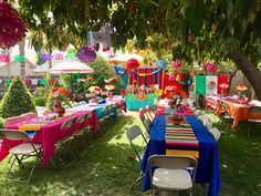 an outdoor party with colorful decorations and tables set up for people to sit down at