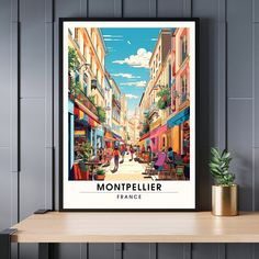 an art print of montpeille france on a shelf next to a potted plant