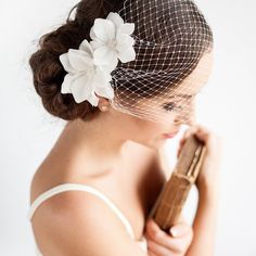 a woman with a veil and flower in her hair is holding a cell phone up to her face