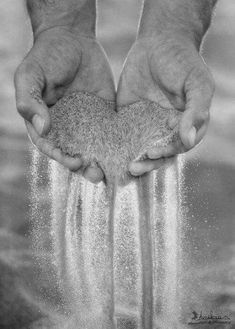 two hands are holding sand in the water