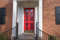 a red door with black shutters on a brick building