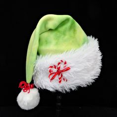 Novelty chartreuse, green tie dye soft poly fleece Santa hat is accented with a soft and fluffy faux fur fabric turn up brim with cotton fabric backing.  Brim is accented with a ribbon tied candy cane and rhinestone bow and there is a snowy white faux fur pompom dangle stitched on the top of the hat, accented with yarn tied red jingle bells. Hat is styled in the classic slouch stocking with generous sizing between 24-25" circumference and a length of 20". If you need additional quantity or a different size hat, send me a message as to availability. Vive Le Vent, Green Santa, Green Tie Dye, Chartreuse Green, Fur Fabric, Rhinestone Bow, Green Tie, Faux Fur Fabric, White Faux Fur