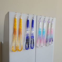 several different colored beads hanging from hooks on a white wall next to a refrigerator freezer