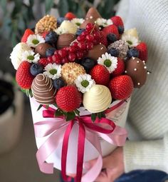 a person holding a bouquet of strawberries and chocolates