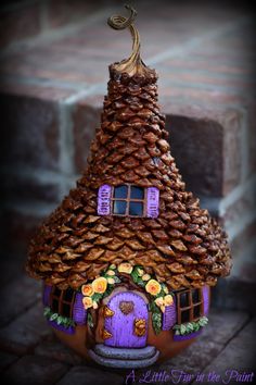 a house made out of pine cones with a purple door and window on the side