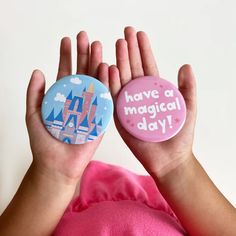 a person holding two buttons in their hands that say have a magic day on them