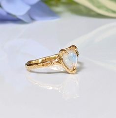 Show your special Love with our delicate Moonstone textured ring. Handcrafted in wax and cast in your choice of Solid Sterling Silver or Solid 14k Gold, our ring features a stunning Pear shape rainbow Moonstone - also the birthstone for June - and artfully set by prongs on an organic textured band, ensuring its uniqueness.T H E ∙ S M A L L ∙ D E T A I L S• Pear shape rainbow Moonstone (6 x 8mm)• Solid 14k Gold textured bandM A T E R I A L ∙ O P T I O N S• Sterling Silver• Solid 14k GoldYou will Heirloom 14k Yellow Gold Moonstone Ring, Handmade Yellow Gold Moonstone Ring In Sterling Silver, Unique Yellow Gold Moonstone Ring, 14k Gold Moonstone Promise Ring, Delicate 14k Gold Moonstone Ring, 14k Gold Moonstone Gemstone Ring For Promise, 14k Gold Moonstone Ring For Promise, Delicate 14k Gold Opal Birthstone Ring, Dainty 14k Yellow Gold Moonstone Ring