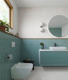 a bathroom with blue and white tiles on the walls, two sinks and a round mirror