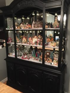 a black china cabinet filled with lots of christmas decorations