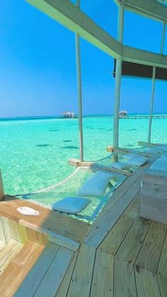 an empty wooden deck in the middle of clear blue water