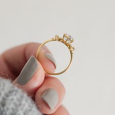 a woman's hand holding a gold ring with two diamonds on the top and bottom