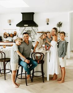 a family is posing for a photo in the kitchen with their two children and one adult