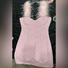 a pink knitted dress with white feathers on it