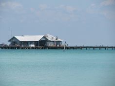 a house sitting on top of a pier next to the ocean