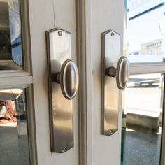 an open door with two knobs on each side and a window in the background