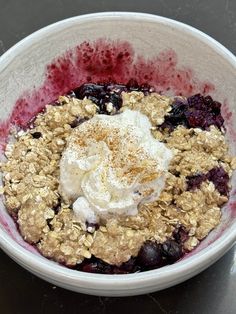 a bowl filled with blueberries and granola topped with whipped cream