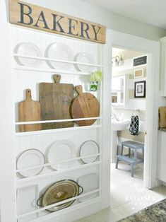 a kitchen with white walls and shelves filled with wooden cutting boards