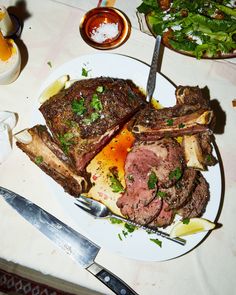 a plate full of meat and vegetables on a table with utensils next to it