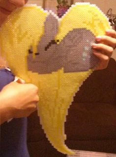 a woman holding up a lego heart shaped like a bird