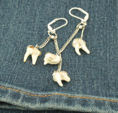 These genuine coyote tooth earrings are an elegant and classy choice for real animal bone taxidermy jewelry. The coyote's molars are surprisingly dainty and adorable little teeth. Each earring has 2 coyote molars dangling from dainty chain in an antique silver finish. These coyote teeth are adorned with a beautiful leaf patterned cap that is molded to fit each individual tooth and hangs securely from a leverback earring clasp closure. -Genuine coyote molar teeth -Antique silver finish -Leaf patt Unique Bone-colored Sterling Silver Jewelry, Unique Bone Colored Sterling Silver Jewelry, Handmade Sterling Silver Jewelry In Bone Color, Unique Bone-colored Nickel-free Earrings, Nickel-free Bone-colored Dangle Earrings, Nickel-free Bone Dangle Earrings, Nickel Free Bone Color Dangle Earrings, Nickel-free Bone Colored Jewelry As Gift, Bone Taxidermy