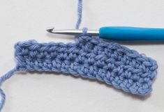 the crochet stitch is being worked on by a blue handled crochet hook