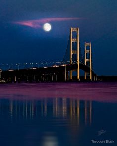 a full moon is seen over the bay bridge