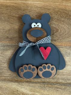 a black bear with a heart and paw print on it's chest sitting on a wooden surface