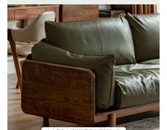 a green leather couch sitting on top of a hard wood floor next to a wooden table