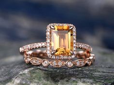 a yellow and white diamond ring sitting on top of a rock with diamonds around it