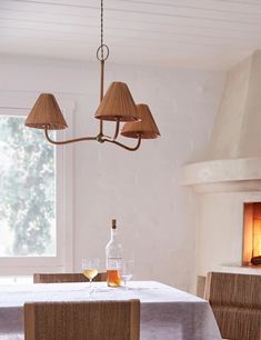 a dining room table with two lamps hanging from it's ceiling and a bottle of wine on the table