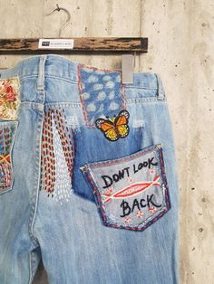 a pair of jeans with embroidered patches on them