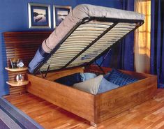 a wooden bed frame with two mattresses in the middle and one under it on top of a hard wood floor