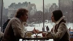 two women sitting at a table in front of a window with snow on the ground