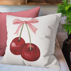 a pillow with two cherries on it and a pink bow tied to the back