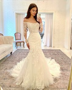 a woman in a white wedding dress taking a selfie with her cell phone while standing in front of a mirror