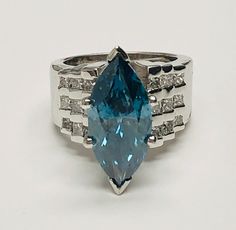 a ring with an aqua colored stone surrounded by white diamonds