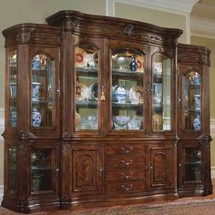 a wooden china cabinet with glass doors and drawers on the top, in a living room