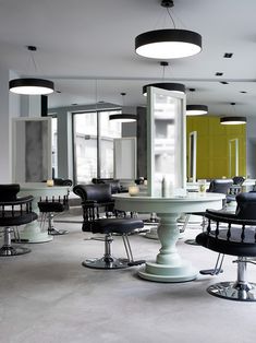 an empty salon with chairs and tables in the middle of it, near large windows