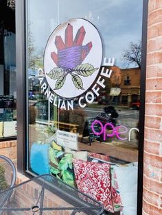 the front window of a coffee shop with chairs and tables in front of it,