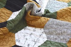 a close up of a quilt on a bed with black and white stripes in the center