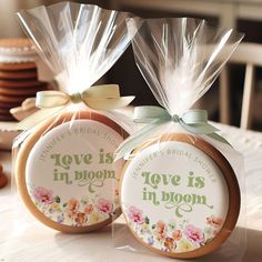 two decorated cookies in plastic bags with ribbons on them sitting on a table next to each other