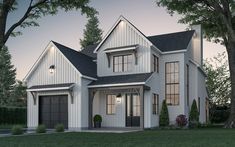 a white house with two garages and trees in the front yard at night time