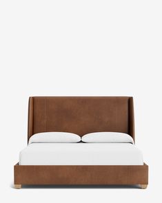 a bed with white pillows and brown leather headboard