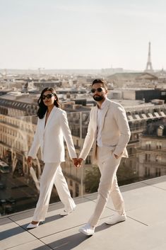 two people holding hands while walking in front of the eiffel tower